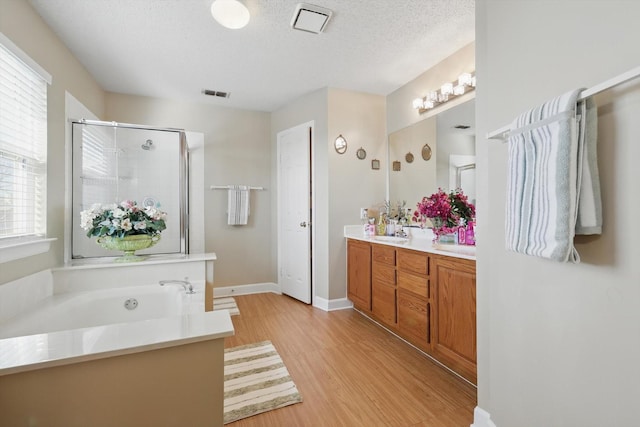 bathroom featuring visible vents, a garden tub, a stall shower, a textured ceiling, and double vanity