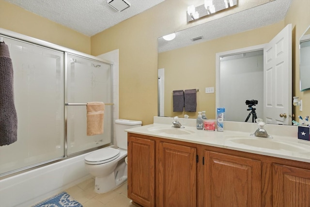 bathroom with tile patterned floors, toilet, a textured ceiling, and a sink