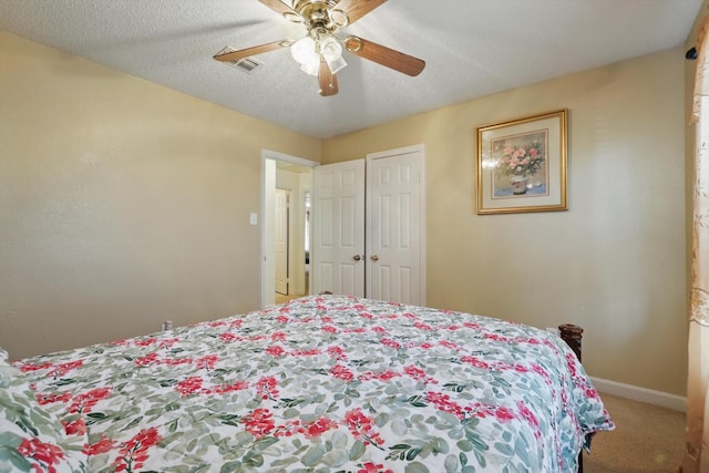 bedroom featuring a ceiling fan, visible vents, baseboards, carpet floors, and a textured ceiling