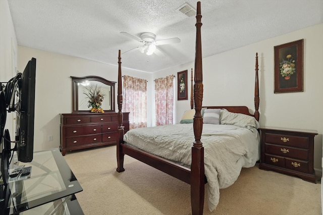 bedroom with a textured ceiling, ceiling fan, visible vents, and light carpet