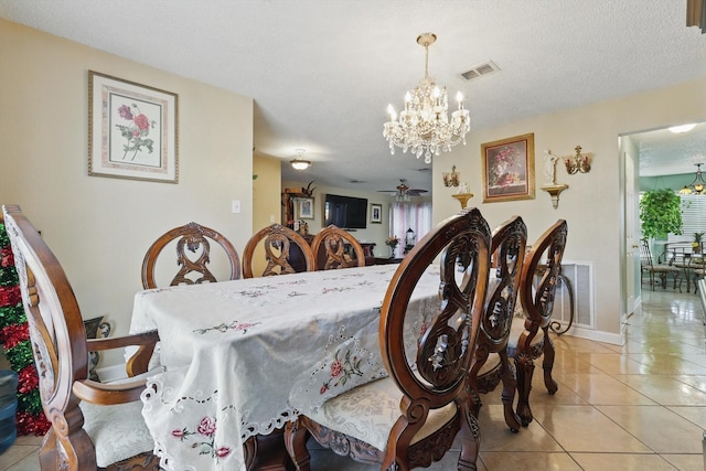 tiled dining space featuring visible vents, ceiling fan with notable chandelier, a textured ceiling, and baseboards