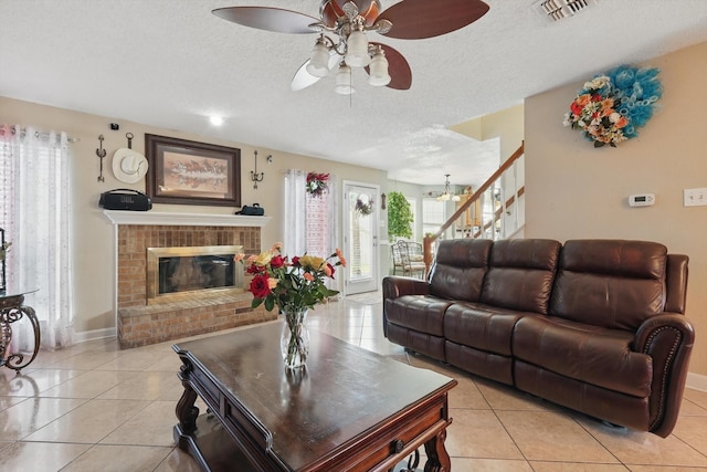 living room with light tile patterned floors, visible vents, a fireplace, stairs, and a textured ceiling