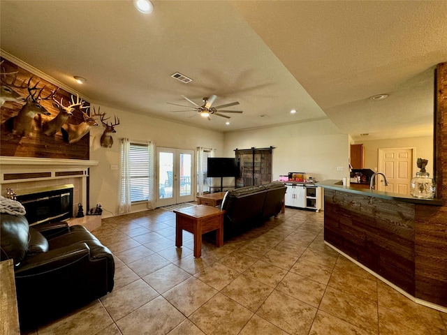 469 Streetman Rd, Royse City, TX 75189 - tiled living room with visible vents, a sink, ceiling fan, a tiled fireplace, and a barn door