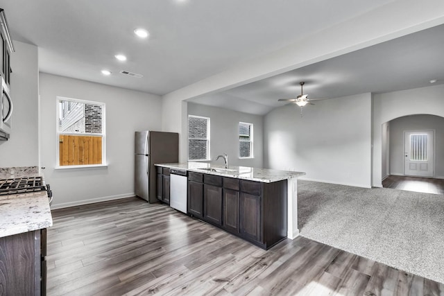 kitchen featuring visible vents, dark brown cabinetry, open floor plan, arched walkways, and stainless steel appliances