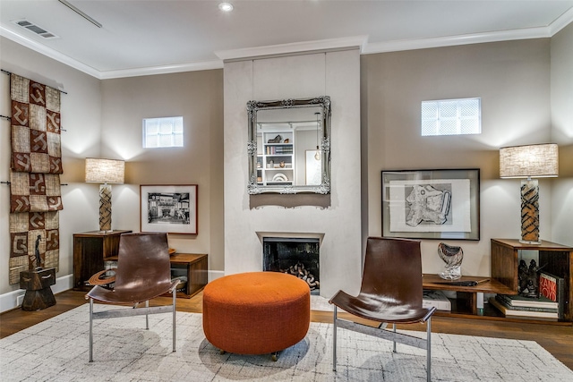 living area featuring wood finished floors, a fireplace, visible vents, and ornamental molding