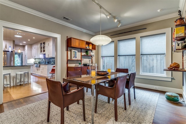 dining area with visible vents, light wood-type flooring, and crown molding