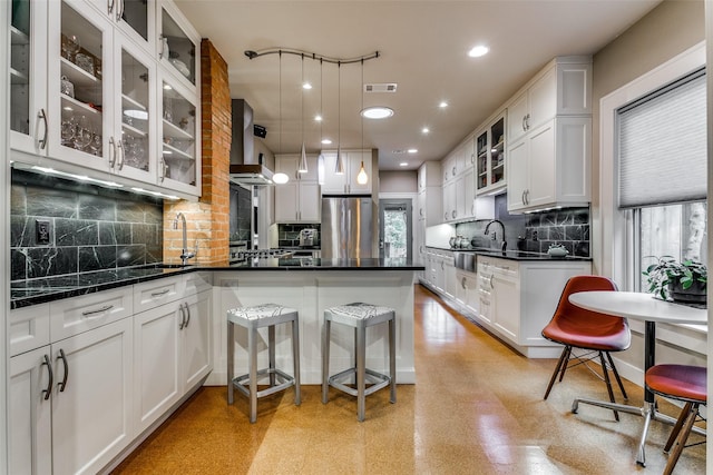 kitchen featuring white cabinets, wall chimney exhaust hood, and freestanding refrigerator