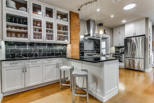 kitchen with freestanding refrigerator, a peninsula, white cabinetry, and wall chimney exhaust hood