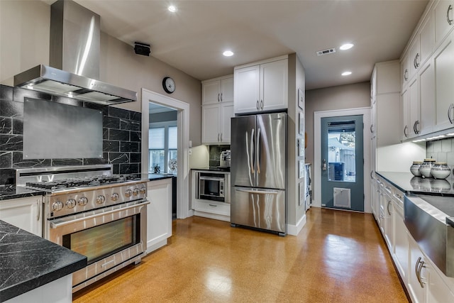 kitchen featuring visible vents, appliances with stainless steel finishes, white cabinets, wall chimney range hood, and light floors