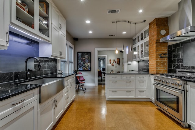 kitchen with visible vents, a sink, a peninsula, wall chimney exhaust hood, and stainless steel gas range