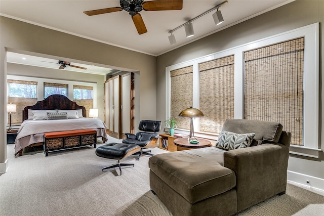 carpeted bedroom featuring baseboards, a ceiling fan, track lighting, and crown molding