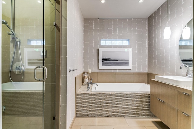 bathroom featuring vanity, a stall shower, tile patterned flooring, a garden tub, and tile walls