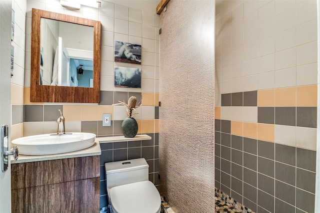 full bath featuring vanity, tile walls, toilet, and a tile shower