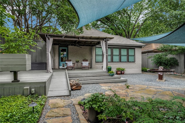 rear view of house with a wooden deck, brick siding, and fence