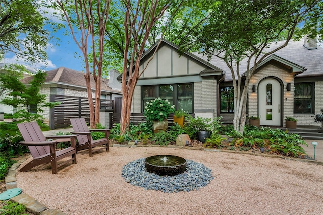 exterior space featuring brick siding, board and batten siding, a shingled roof, fence, and a patio