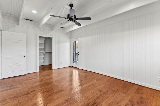 unfurnished bedroom featuring baseboards, hardwood / wood-style floors, beam ceiling, a closet, and a ceiling fan