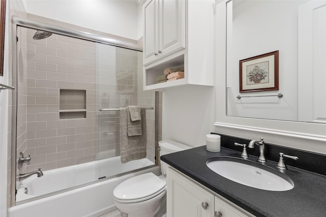 full bath featuring vanity, toilet, and bath / shower combo with glass door