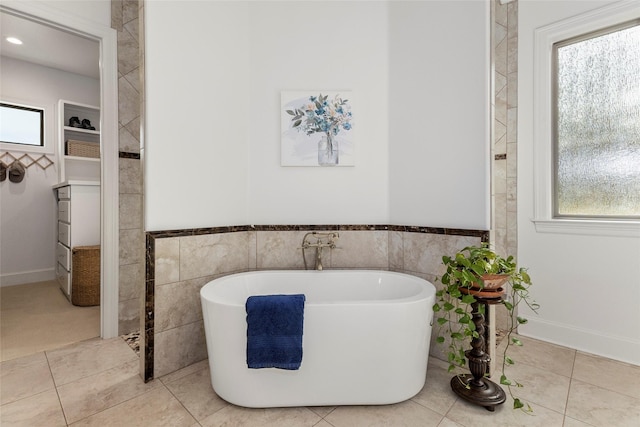 full bathroom with tile patterned floors, a freestanding tub, tile walls, and a wainscoted wall