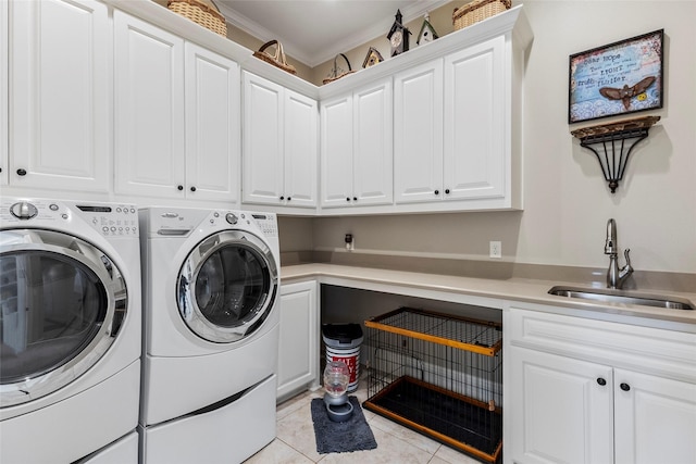 washroom with ornamental molding, a sink, washer and dryer, cabinet space, and light tile patterned floors