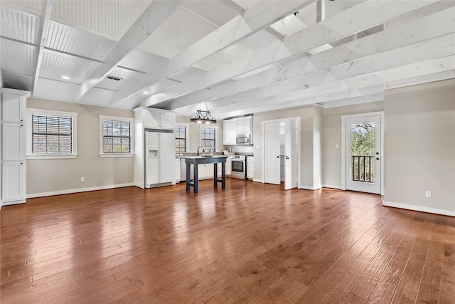 unfurnished living room with visible vents, baseboards, dark wood-type flooring, and plenty of natural light