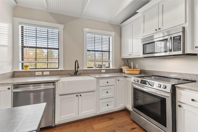 kitchen featuring wood finished floors, a sink, stainless steel appliances, light countertops, and white cabinets