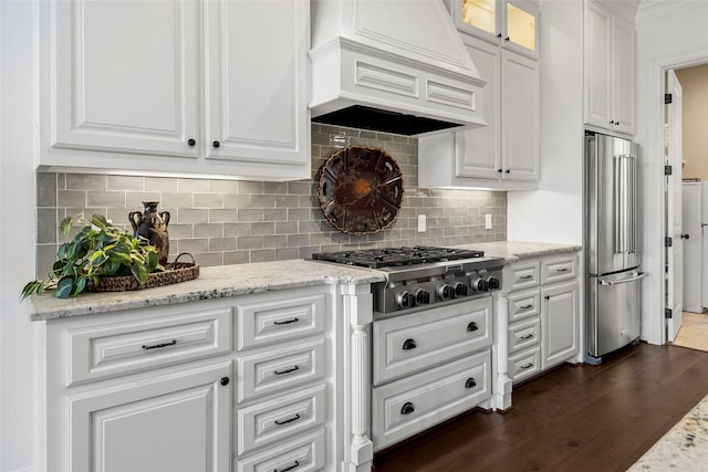 kitchen with dark wood-style floors, premium range hood, appliances with stainless steel finishes, white cabinetry, and tasteful backsplash