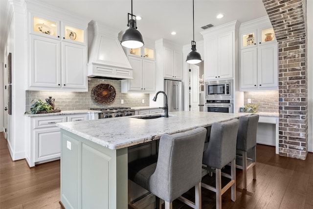 kitchen featuring dark wood-style floors, visible vents, custom exhaust hood, stainless steel appliances, and a sink