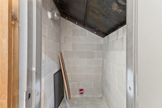 bathroom with concrete flooring and concrete block wall