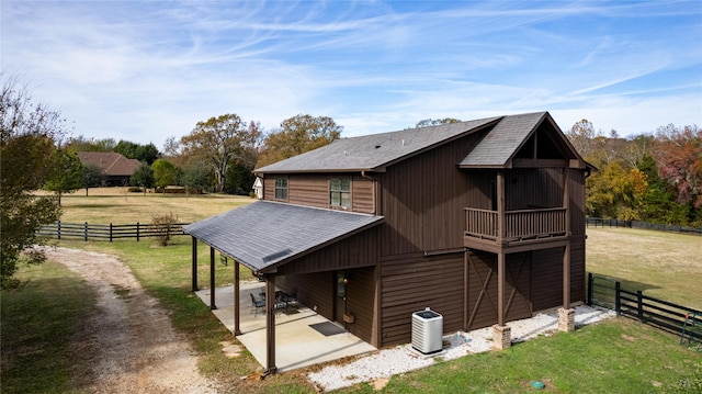 view of side of property featuring a yard, a patio area, fence, and a shingled roof