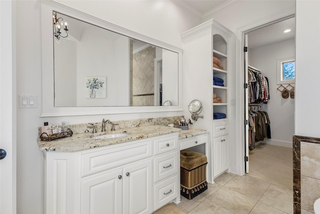 bathroom featuring a walk in closet, ornamental molding, tile patterned flooring, baseboards, and vanity