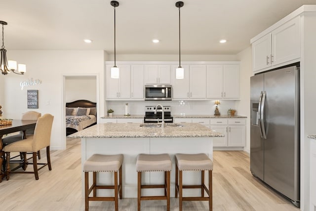 kitchen featuring a sink, appliances with stainless steel finishes, white cabinets, and light wood finished floors