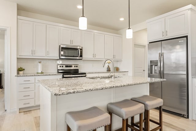 kitchen with tasteful backsplash, stainless steel appliances, light wood-style floors, and a sink