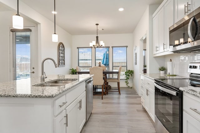 kitchen featuring light wood finished floors, tasteful backsplash, stainless steel appliances, white cabinetry, and a sink