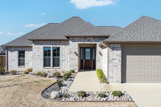 french provincial home featuring a garage, brick siding, and a shingled roof