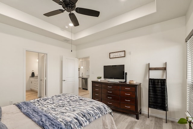 bedroom with a raised ceiling, light wood-style floors, visible vents, and baseboards