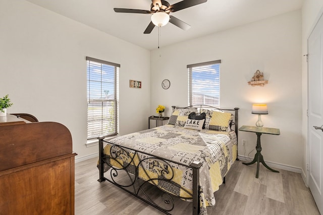 bedroom featuring multiple windows, light wood-type flooring, and baseboards