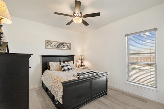 bedroom featuring a ceiling fan, light wood-style floors, and baseboards