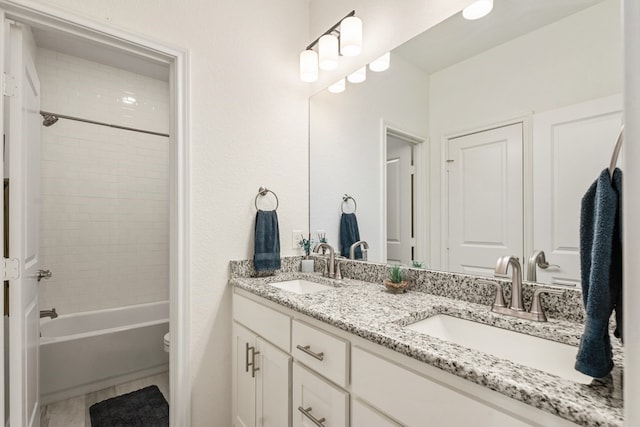 bathroom featuring a sink, bathing tub / shower combination, toilet, and double vanity