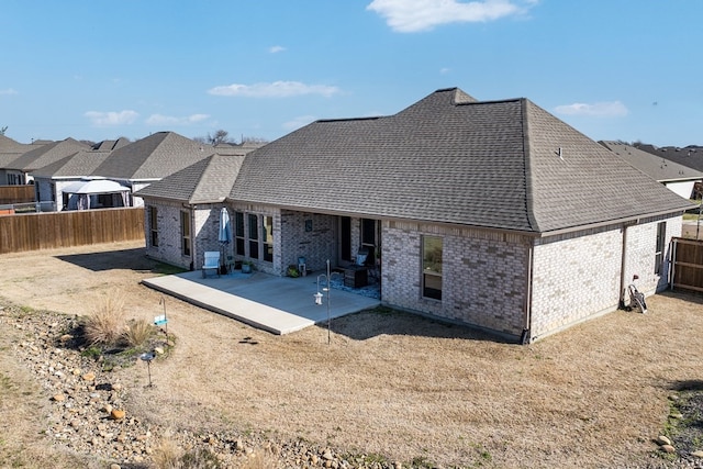 back of property with a patio, brick siding, a fenced backyard, and a shingled roof