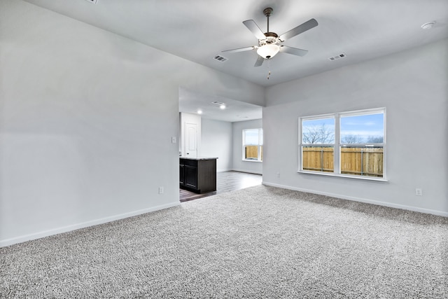 unfurnished living room featuring visible vents, carpet floors, baseboards, and a ceiling fan