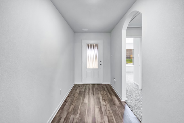 doorway featuring visible vents, arched walkways, dark wood-style flooring, and baseboards