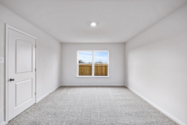 carpeted empty room featuring baseboards