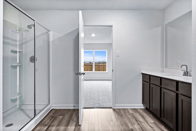 bathroom with baseboards, wood finished floors, a stall shower, and vanity