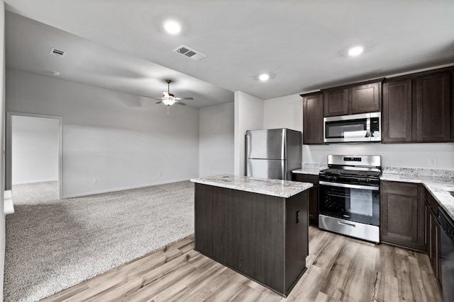 kitchen with visible vents, a kitchen island, open floor plan, stainless steel appliances, and dark brown cabinets