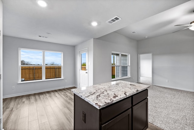 kitchen with open floor plan, visible vents, and light stone countertops