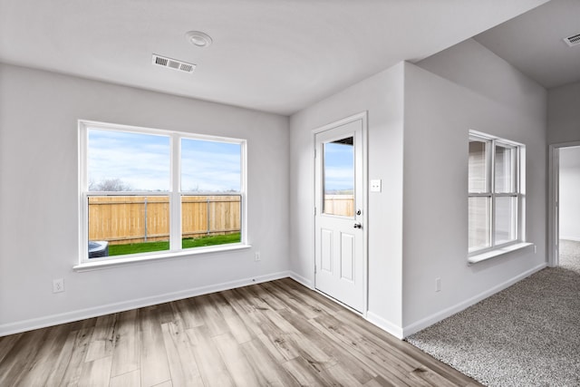 foyer entrance featuring wood finished floors, baseboards, and visible vents