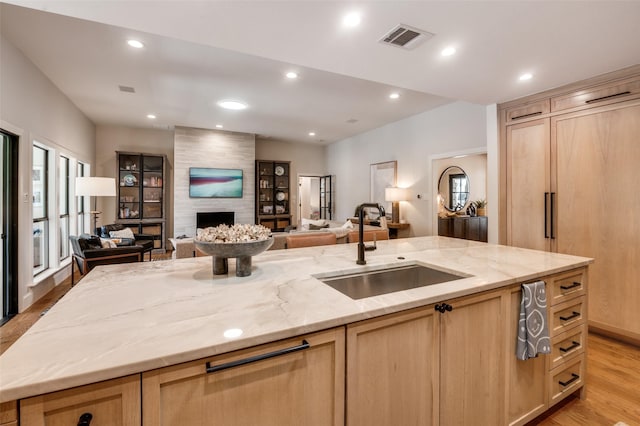 kitchen featuring a sink, open floor plan, and light brown cabinetry