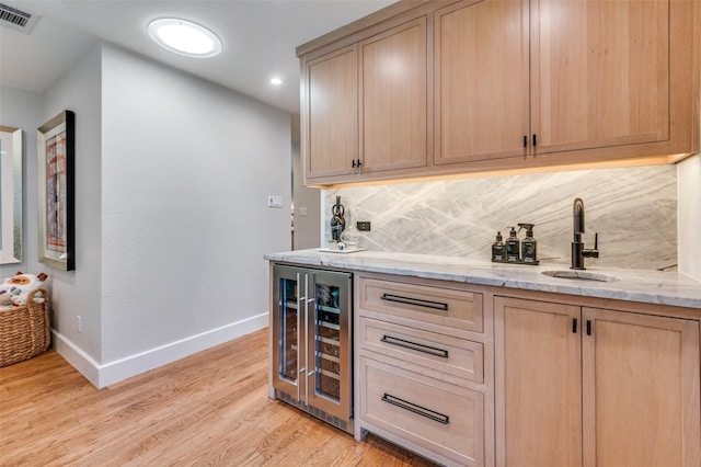 bar featuring light wood finished floors, visible vents, tasteful backsplash, wine cooler, and a sink