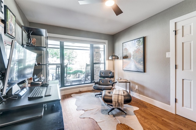 home office with a ceiling fan, wood finished floors, and baseboards