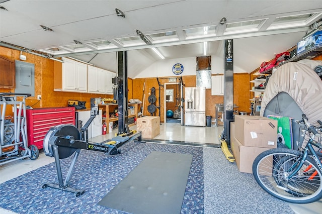 garage featuring a workshop area, electric panel, and high end fridge